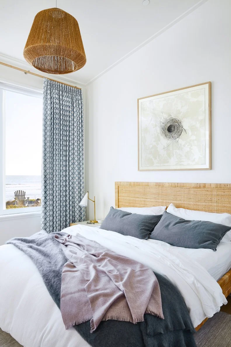 Quiet coastal bedroom with white crown molding, soft natural light, and woven lighting