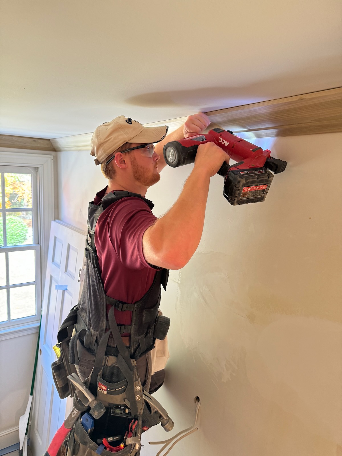 Logan Flynn installing crown molding with a nail gun